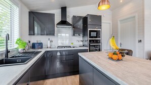 Una cucina moderna con mobili neri, un'isola centrale, un fornello e un forno a microonde.