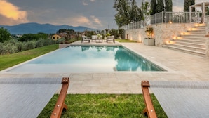 A swimming pool with a view of mountains and a stone staircase leading to a covered area. - Villa Sunkiss Winery (Montecarlo)
