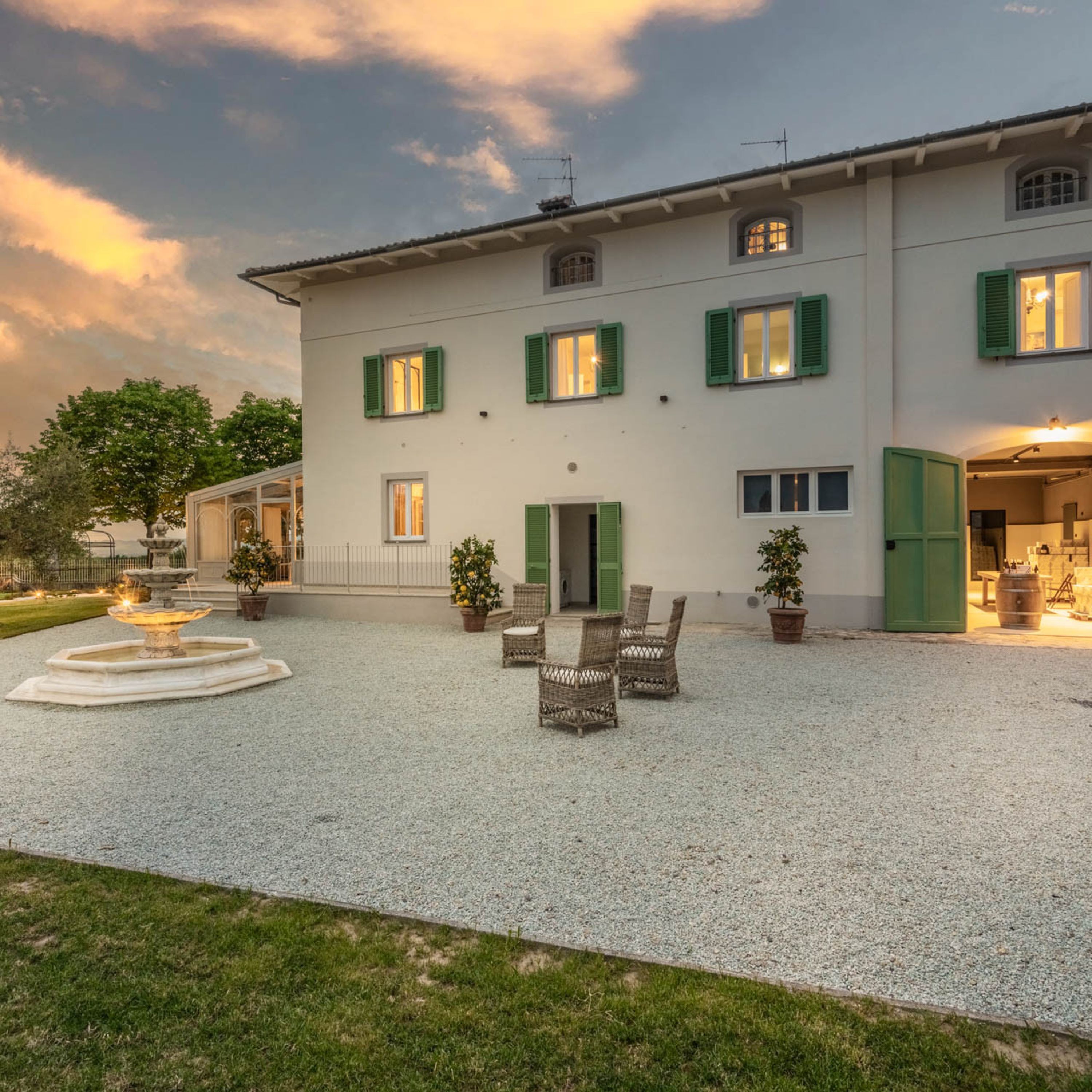 A two-story building with a gravel courtyard, outdoor seating, and a fountain.