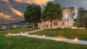 A modern house with a well-maintained lawn, a pergola, and a pathway leading to the entrance. - Villa Sunkiss Winery (Montecarlo)