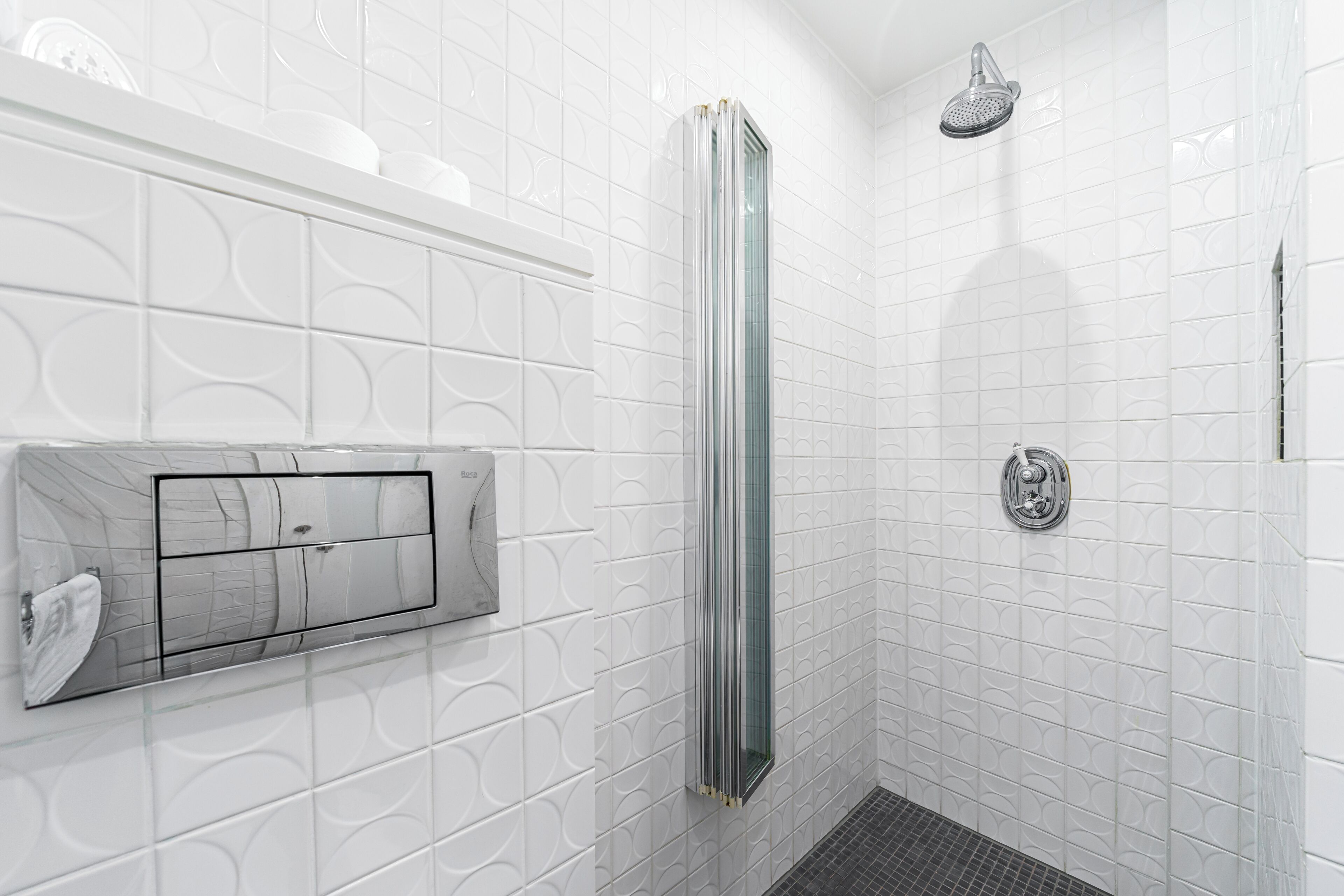 A modern bathroom with a glass shower enclosure, a built-in toilet, and a wall-mounted sink.