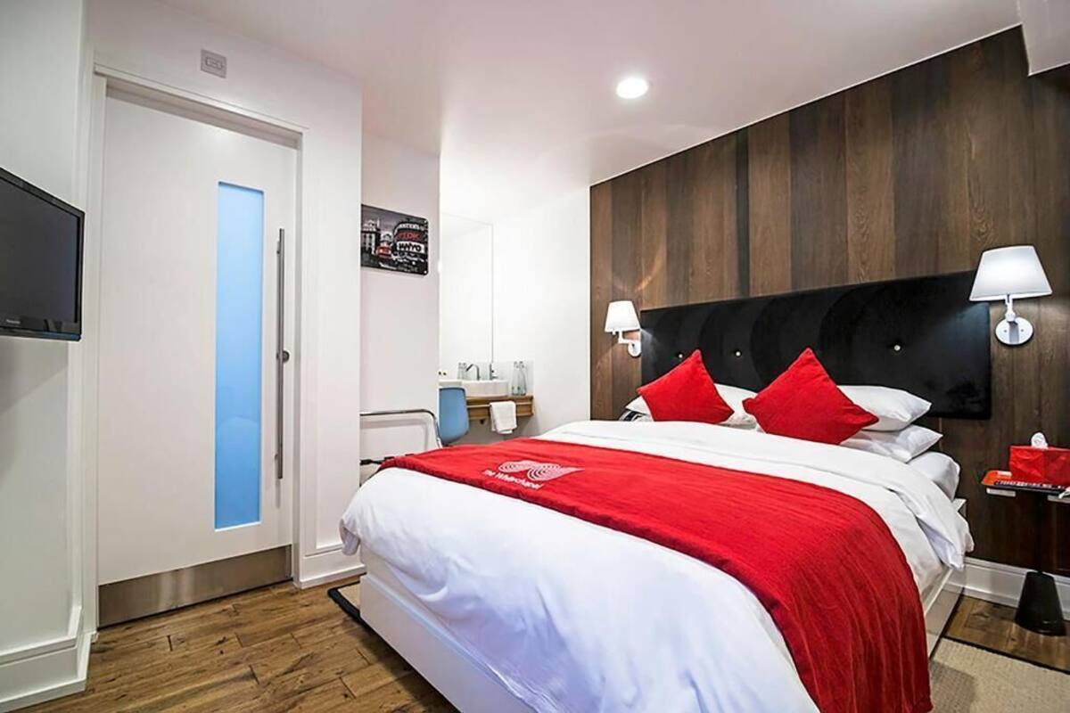 A hotel room with a bed, a television, a bathroom, and a wooden wall.