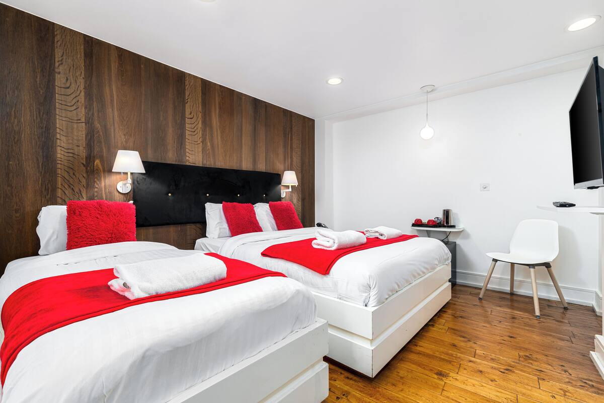 A hotel room with two beds, wooden paneling on the wall, a TV, a desk, and a chair.