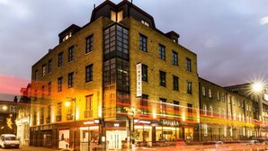 A multi-story hotel with a brick facade, large windows, and a sign indicating it is a hotel. - The Whitechapel (London)