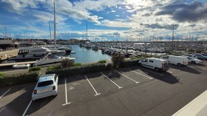 A marina with boats docked, a parking area, and a clear sky.