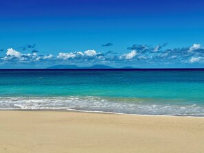 A beach with clear turquoise waters and a sandy shore.
