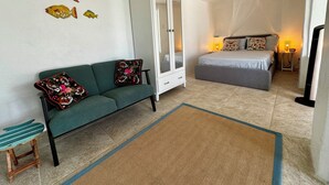 Et værelse med en grøn sofa, en seng, et skab og et lille bord.