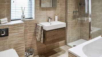 A modern bathroom with a glass-enclosed shower, a white sink, and a large bathtub.