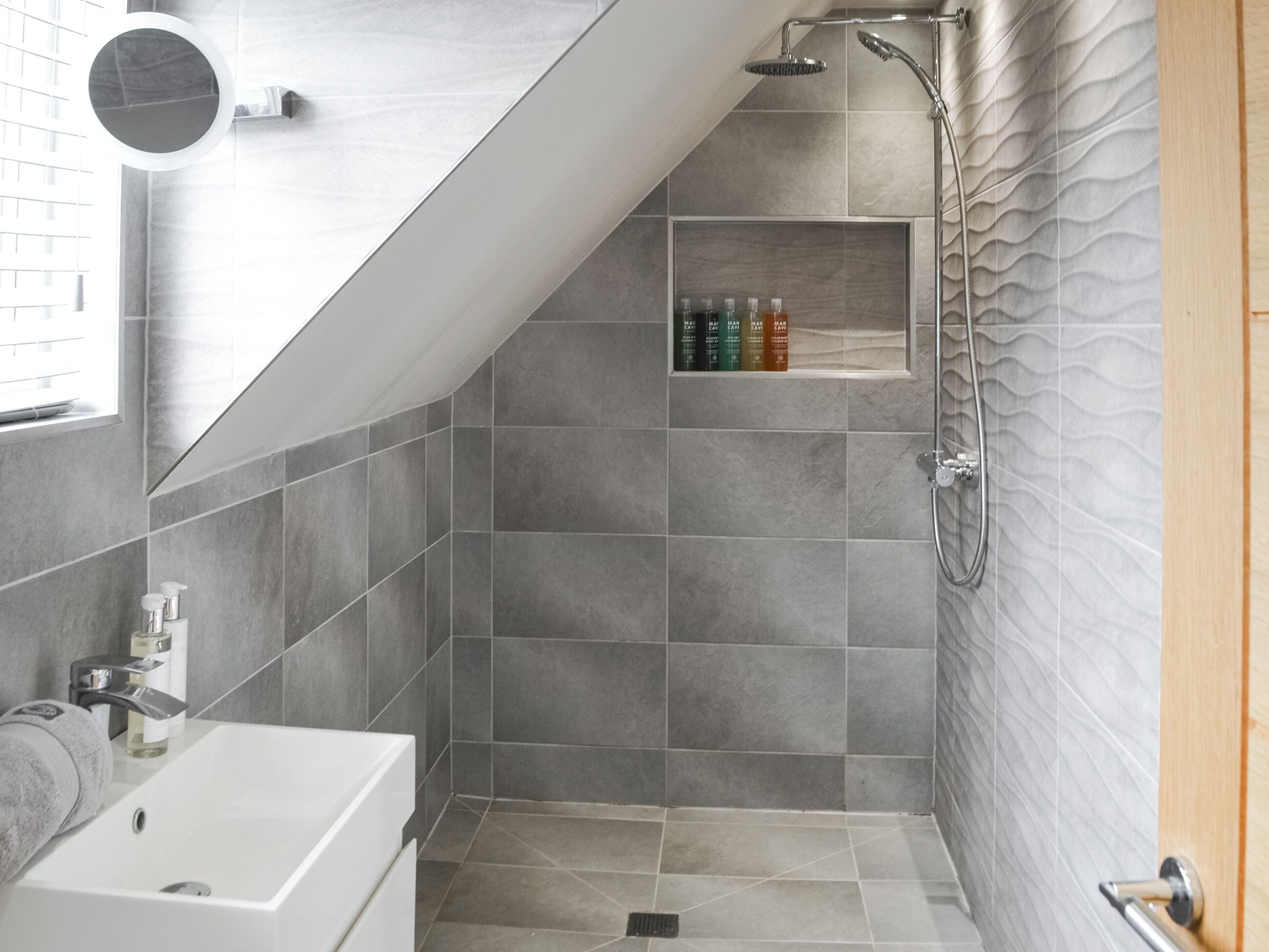 Een moderne badkamer met een douche, een wastafel en een spiegel.
