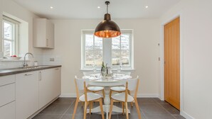 Una cocina moderna con una mesa de comedor, sillas y una lámpara colgante.