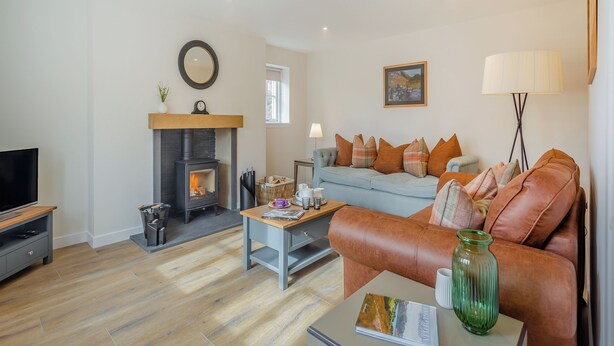 Una sala de estar con chimenea, sofá, mesa de centro y televisor.