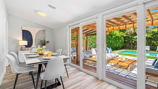 A modern dining area with a table, chairs, and a view of a pool and garden through large sliding glass doors. - Sep Discount! Heated Pool, Close to Atlantic (Delray Beach)