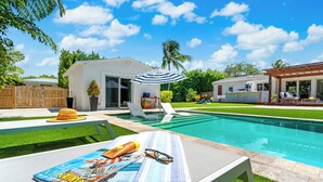 A backyard with a swimming pool, lounge chairs, and a small house. - Sep Discount! Heated Pool, Close to Atlantic (Delray Beach)