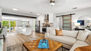A modern living room with a large brown leather sofa, a coffee table with a tray, and a kitchen in the background. - Sep Discount! Heated Pool, Close to Atlantic (Delray Beach)