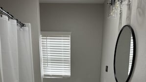 Uma casa de banho com chuveiro, sanita, lavatório e uma citação emoldurada na parede.