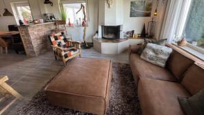 A cozy living room with a fireplace, a stone bar, and a comfortable seating area. - Haus Aktiv Winterberg, Garten Apartment, Www.haus-aktiv.de - 2-6 Personen (Winterberg)