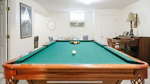 A pool table with a cue ball, surrounded by a sofa and a piano. - Ultimate relaxation spot with steam room, close to the beach. Family-friendly (Nantucket)