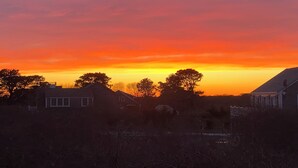 A sunset over a residential area with houses and trees silhouetted against the sky. - Ultimate relaxation spot with steam room, close to the beach. Family-friendly (Nantucket)