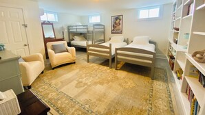 A bedroom with bunk beds, a chair, a bookshelf, and a patterned rug. - Ultimate relaxation spot with steam room, close to the beach. Family-friendly (Nantucket)