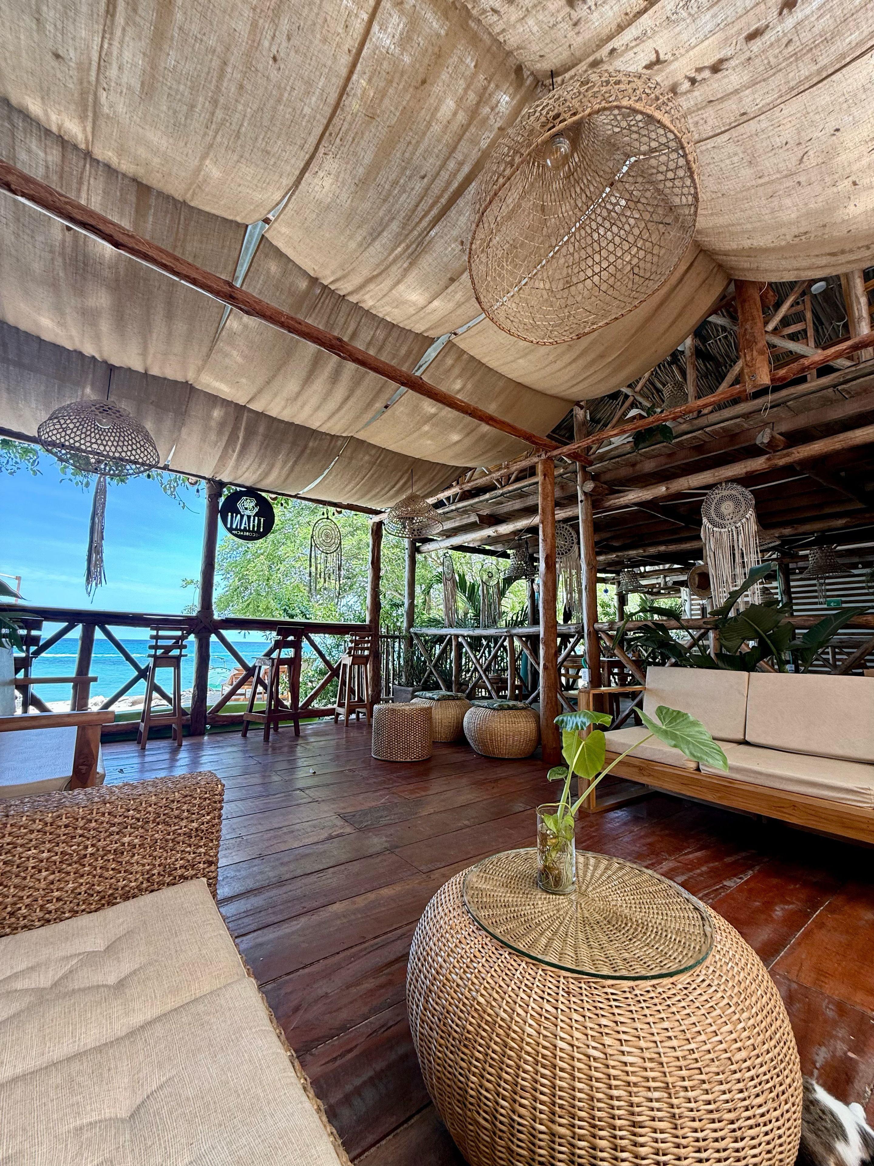 An outdoor seating area with wicker furniture, a canopy, and a view of the ocean.