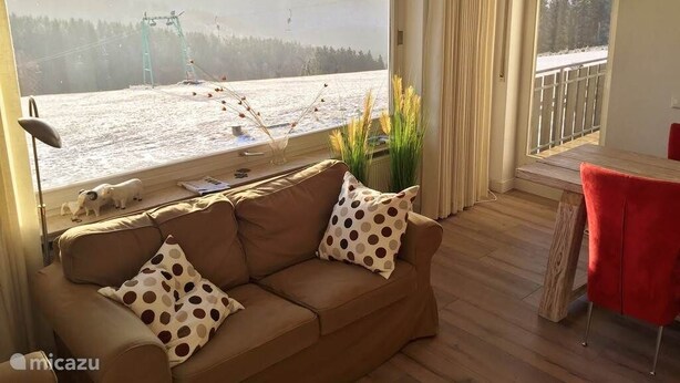 Et værelse med sofa, spisebord og udsigt til et sneklædt landskab.