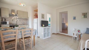 Een moderne keuken met een eethoek, een televisie en een gezellige zithoek met een bed en een klein tafeltje.