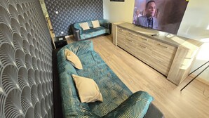 Un salon moderne avec deux canapés, un meuble en bois et un grand téléviseur à écran plat.