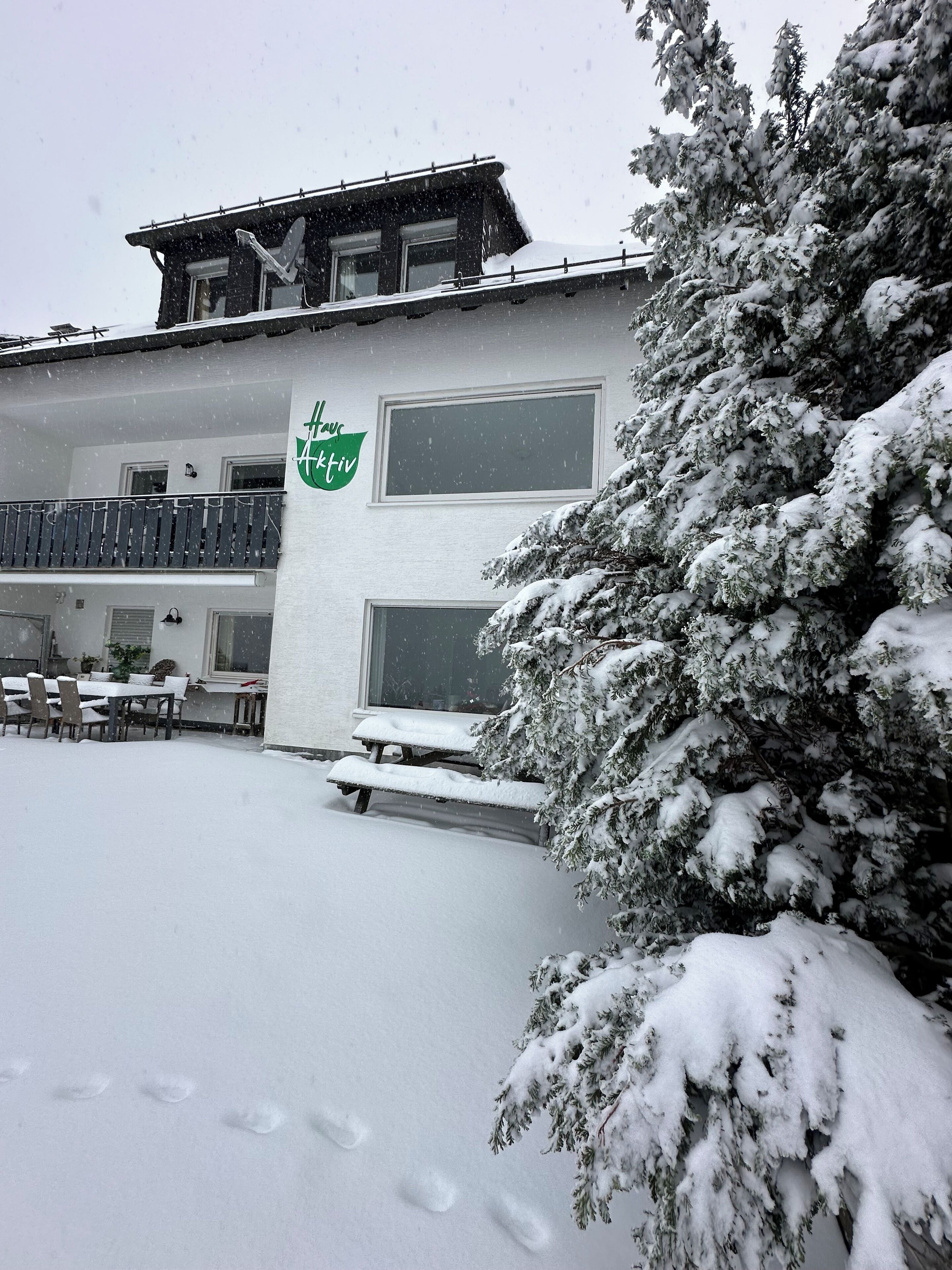 Ein Gebäude mit einem Schild, auf dem 'Fachwerk' steht, und ein verschneiter Außenbereich mit einer Bank und einem Tisch.