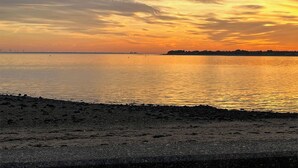 Une plage avec une mer calme et un coucher de soleil.