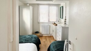 Une petite pièce avec deux lits, un radiateur, un lavabo et un miroir.