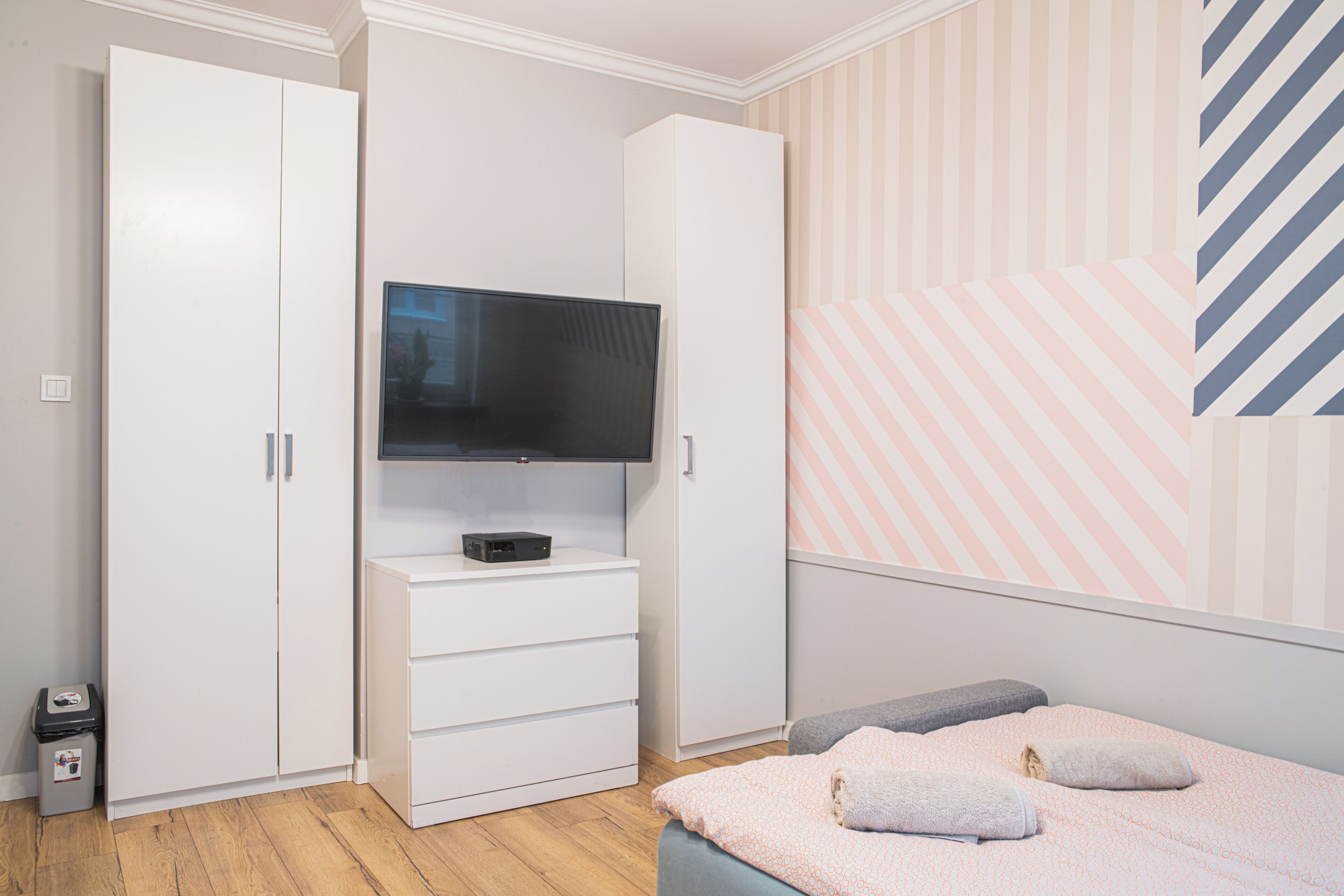 Una camera da letto con un letto, una televisione su un mobile, un armadio e un cestino.