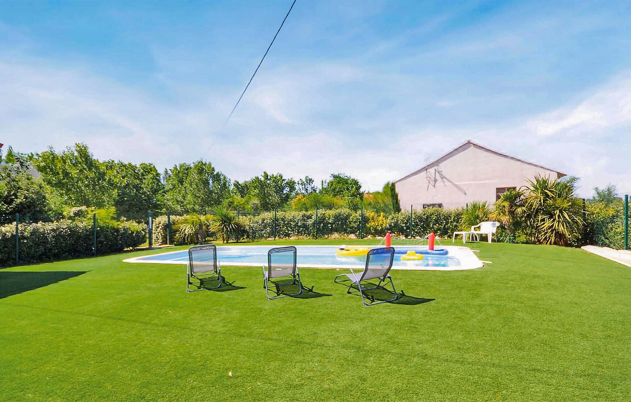 A pool area with three lounge chairs, a small inflatable pool, and a building in the background.