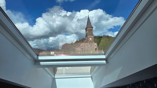 Ein Zimmer mit Oberlicht, einem Bett und Blick auf eine Kirche mit einem Glockenturm.