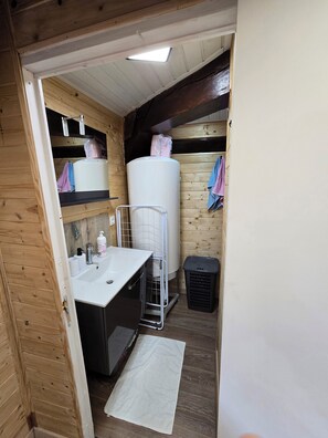 A compact bathroom with a sink, mirror, and a large water heater.