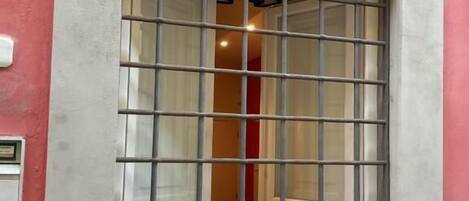 Ein Fenster mit Gitterstäben, eine rosa Wand und ein Lichtschalter auf der linken Seite.