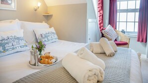 A neatly made bed with pillows, a tray with croissants and a cup, and a vase with flowers. - Discover coastal tranquility in Millhouse Cottage on Budle Bay. (Bamburgh)