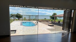 A modern room with a large sliding glass door leading to an outdoor area with a swimming pool and a view of a lake.