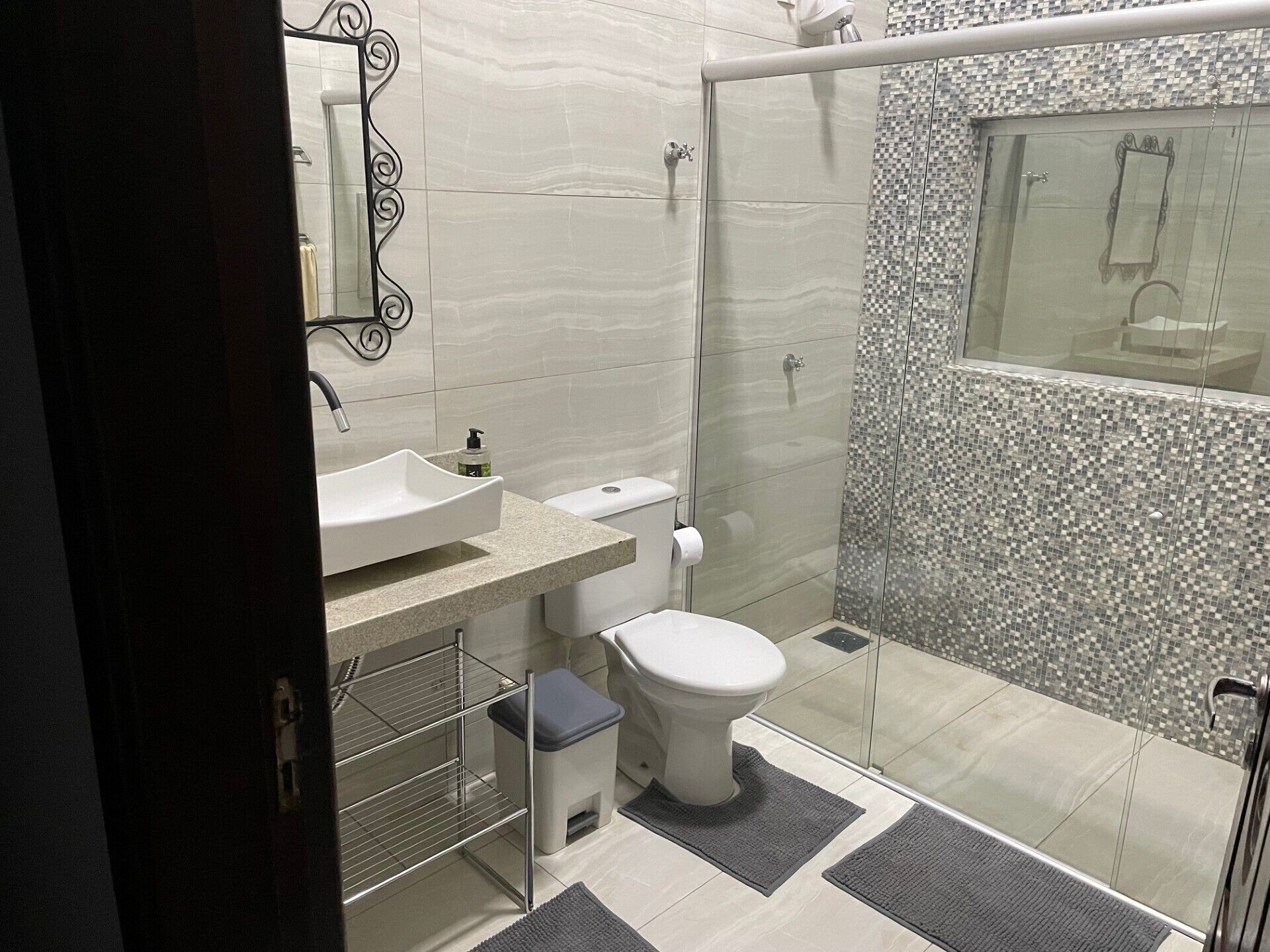 Un bagno moderno con lavandino, water e doccia bianchi.