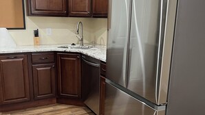 Una cocina con armarios de madera, un refrigerador de acero inoxidable y una encimera de granito.