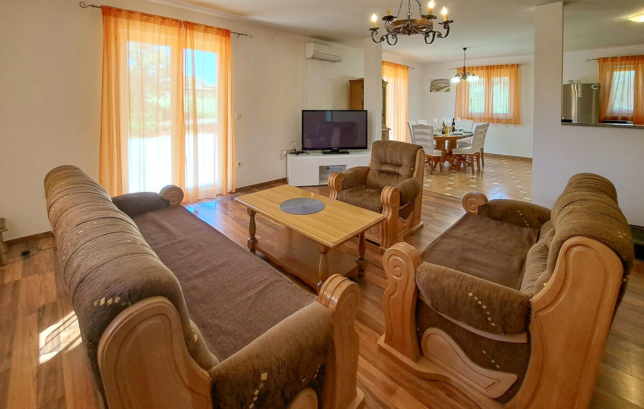 A living room with a sofa set, a coffee table, a TV, and a dining area with chairs and a table.