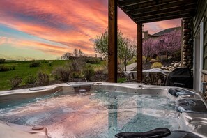 Ein Whirlpool mit Blick auf einen Garten und ein Haus bei Sonnenuntergang.
