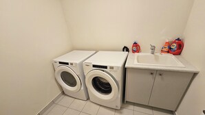 Ein Waschbereich mit zwei Waschmaschinen und einem Waschbecken.