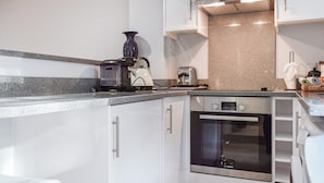 Eine moderne Küche mit weißen Schränken, einem Bosch-Backofen, einer Kaffeemaschine und einem Toaster.