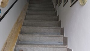 A staircase with a wooden handrail and a white wall with framed pictures. - Stella's House Bed & Breakfast  (Sabbio Chiese)