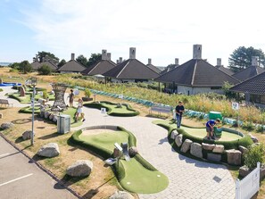 Un parcours de minigolf avec des trous numérotés, un chemin et des aménagements paysagers environnants.