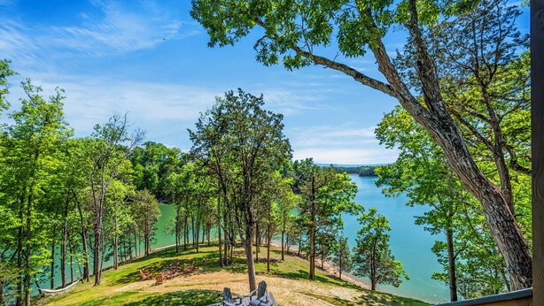 A lakeside property with a deck, chairs, and a hammock.