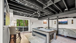 A spacious room with a pool table, a sofa, and a view of the outdoors.