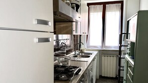 Eine kleine Küche mit Gasherd, Spüle und einem Fenster mit Vorhängen.