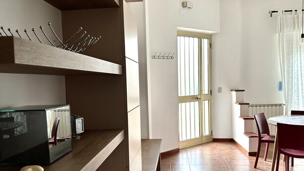 Eine moderne Küche mit Einbauofen, ein Essbereich mit rundem Tisch und Stühlen sowie eine Tür mit Fenster.