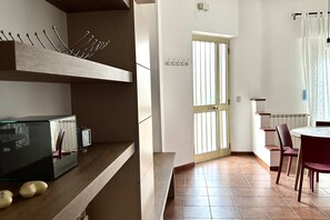 A modern kitchen with a built-in oven, a dining area with a round table and chairs, and a door with a window.